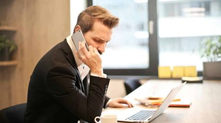 Man Having a Phone Call In-front of a Laptop